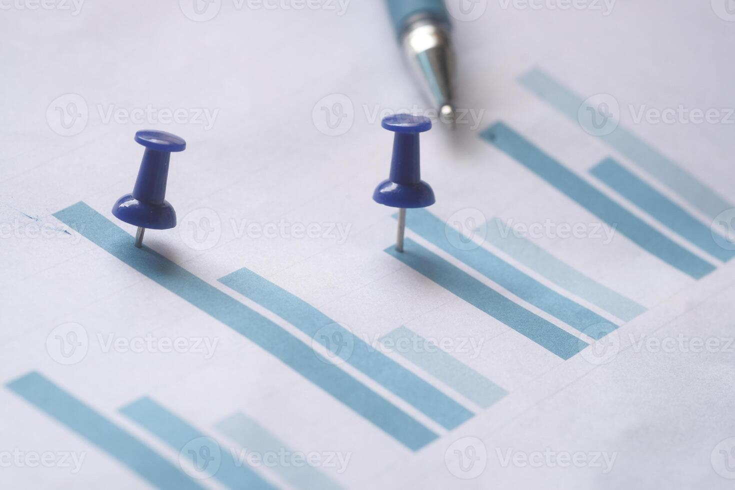 Detailed Business Chart Displayed with Colorful Push Pins and a Pen Resting on Paper Surface photo