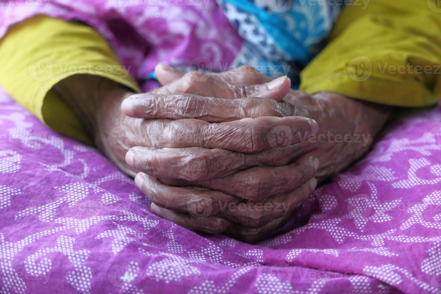 Elderly Hands Gently Resting on a Beautifully Colorful Piece of Fabric Displaying Patterns photo
