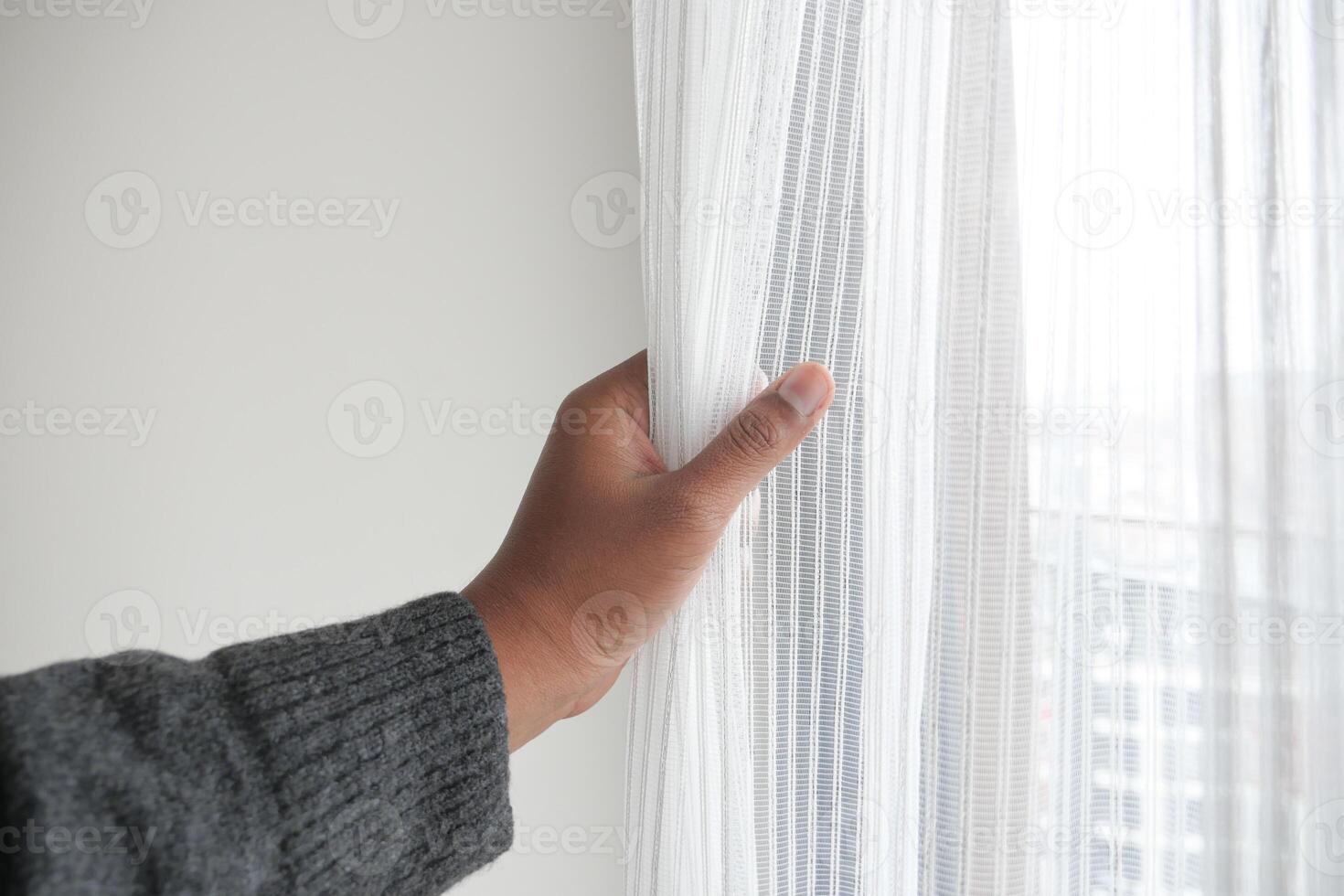 Gently Hand Opening Sheer Curtains to Brighten and Invigorate a Room with Daylight photo
