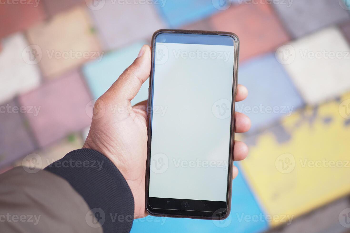 A smartphone in hand rests on a colorful paved surface, creating an inviting scene photo