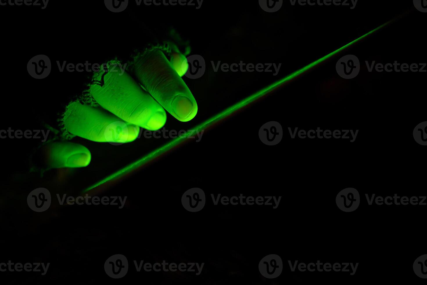 An Illuminated Green Hand Gripping a Blade in the Depths of Darkness Surrounding It photo
