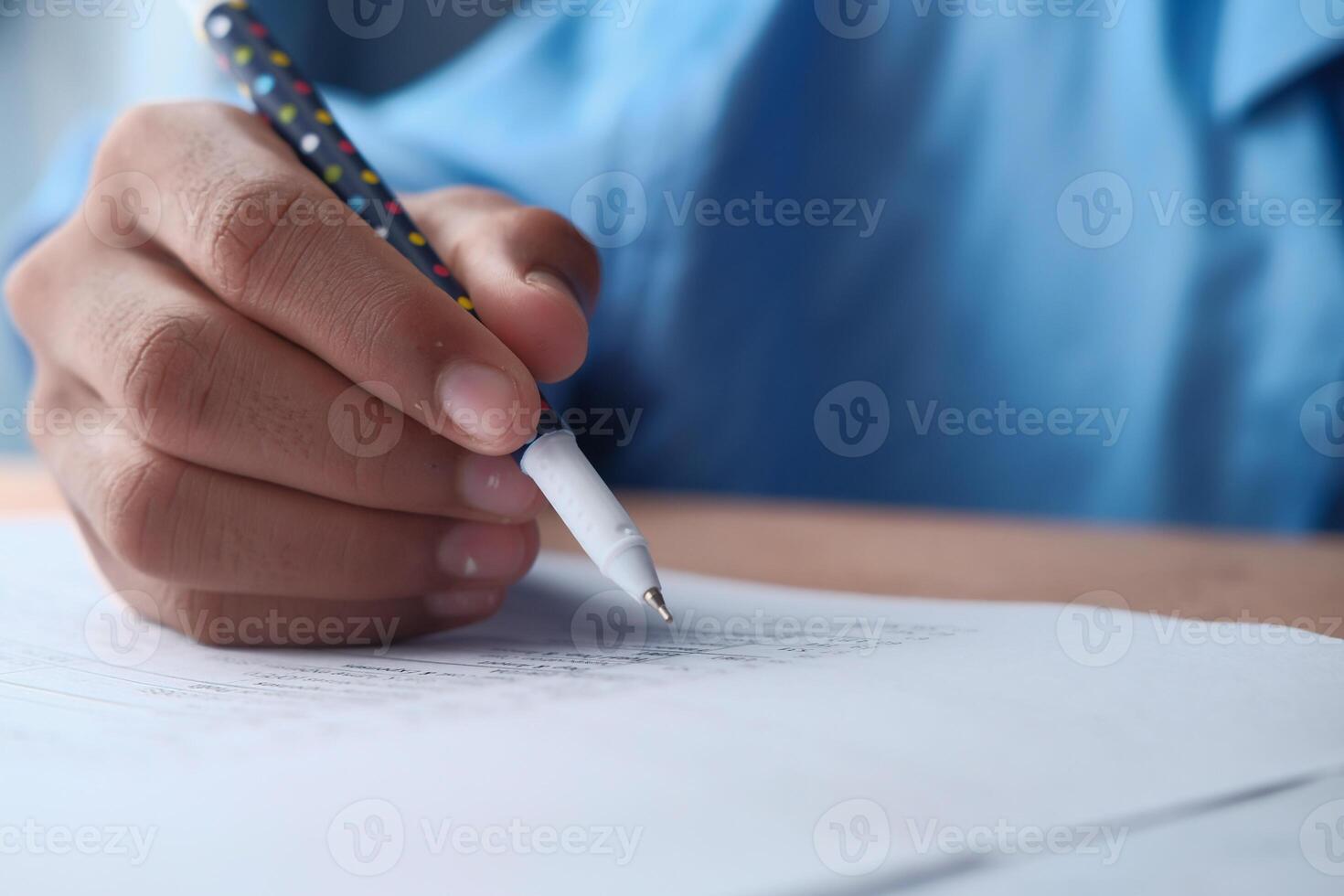 A person writes creatively with a colorful pen on paper, showing focus in their work photo