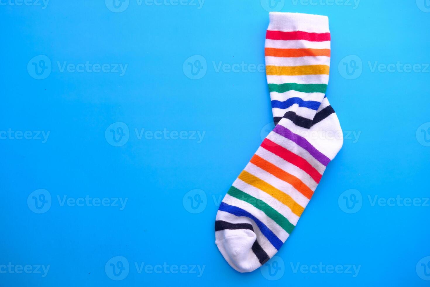 A colorful rainbow sock on a bright blue background creates an eyecatching visual photo