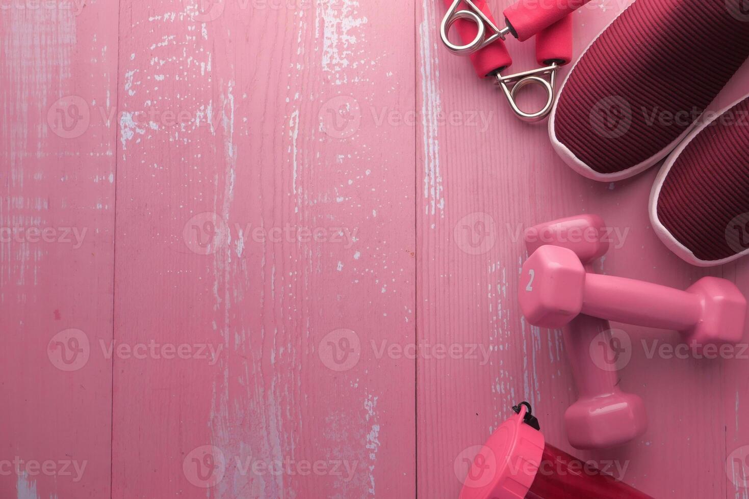 A pink background with essential fitness items like dumbbells and sneakers for active people photo