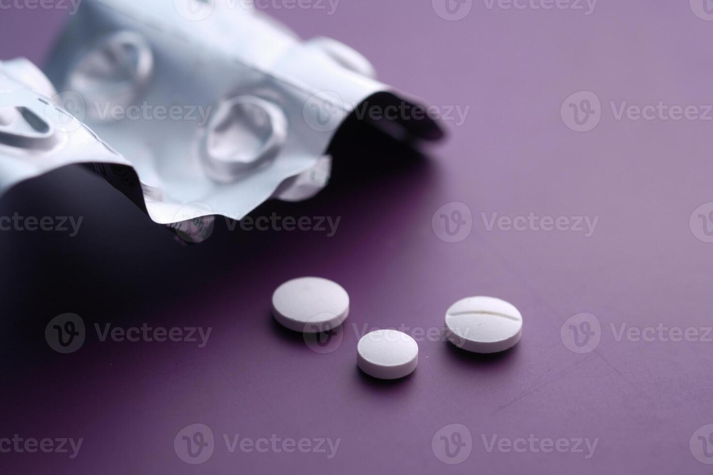 A closeup of white pills in a blister pack on a vibrant purple background, evoking health photo
