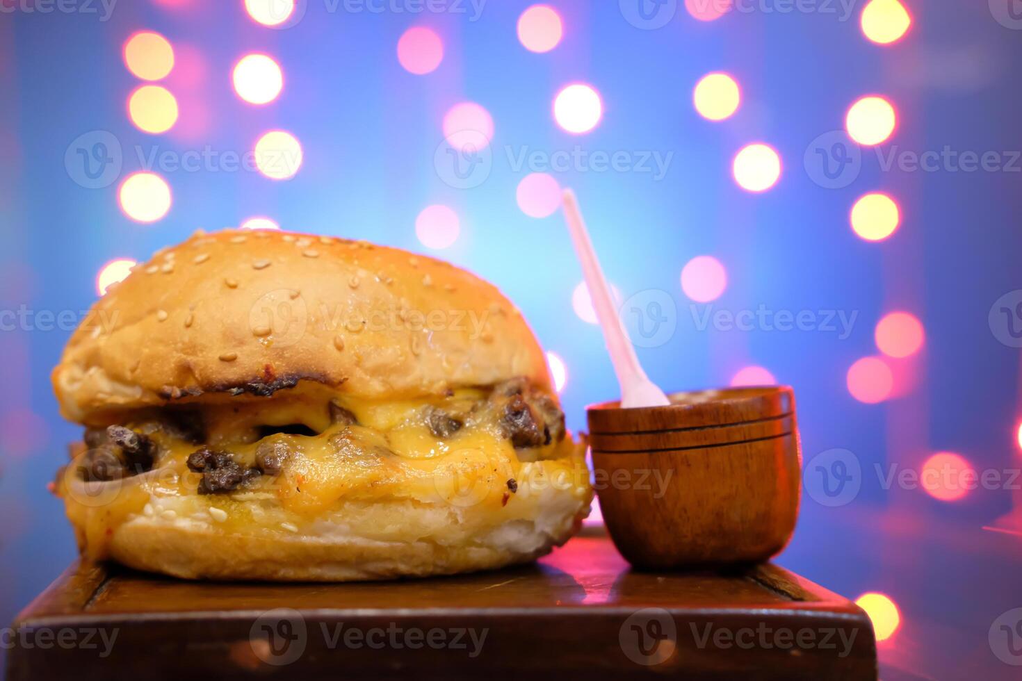 A mouthwatering, delicious cheeseburger served with tasty condiments on a rustic wooden platter photo