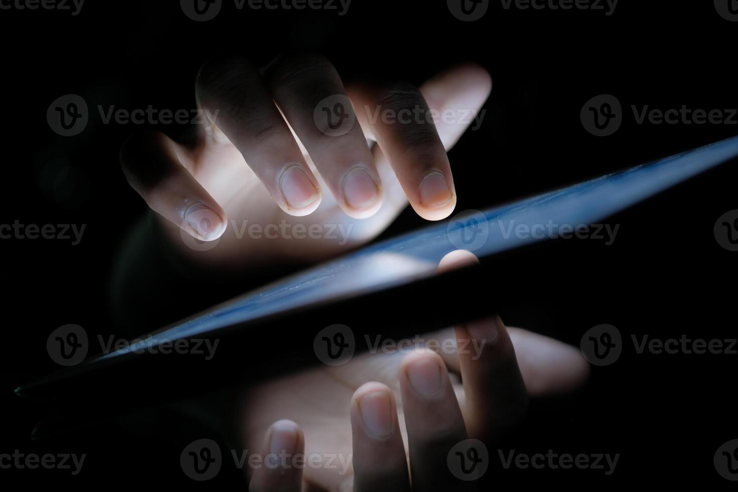 A persons hands interact with a tablet screen in low light, creating an engaging atmosphere photo