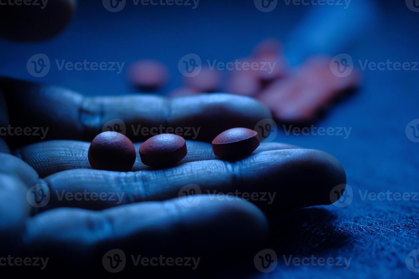 A hand is holding red pills illuminated by blue light, suggesting healthrelated themes photo