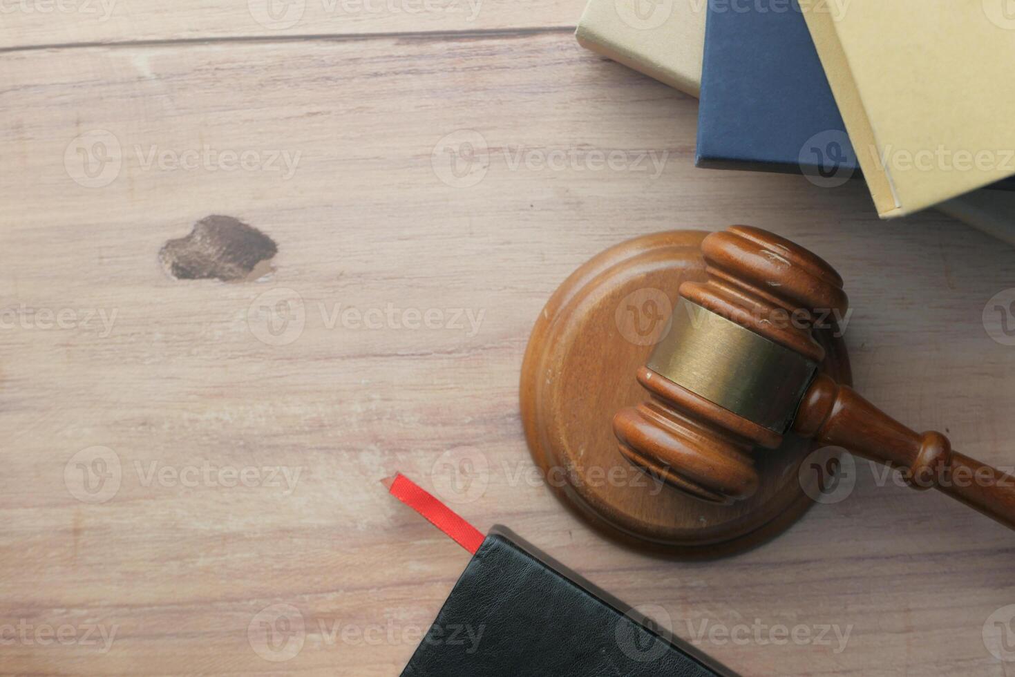 A Legal Gavel positioned on a Wooden Table alongside various Law Books for reference photo