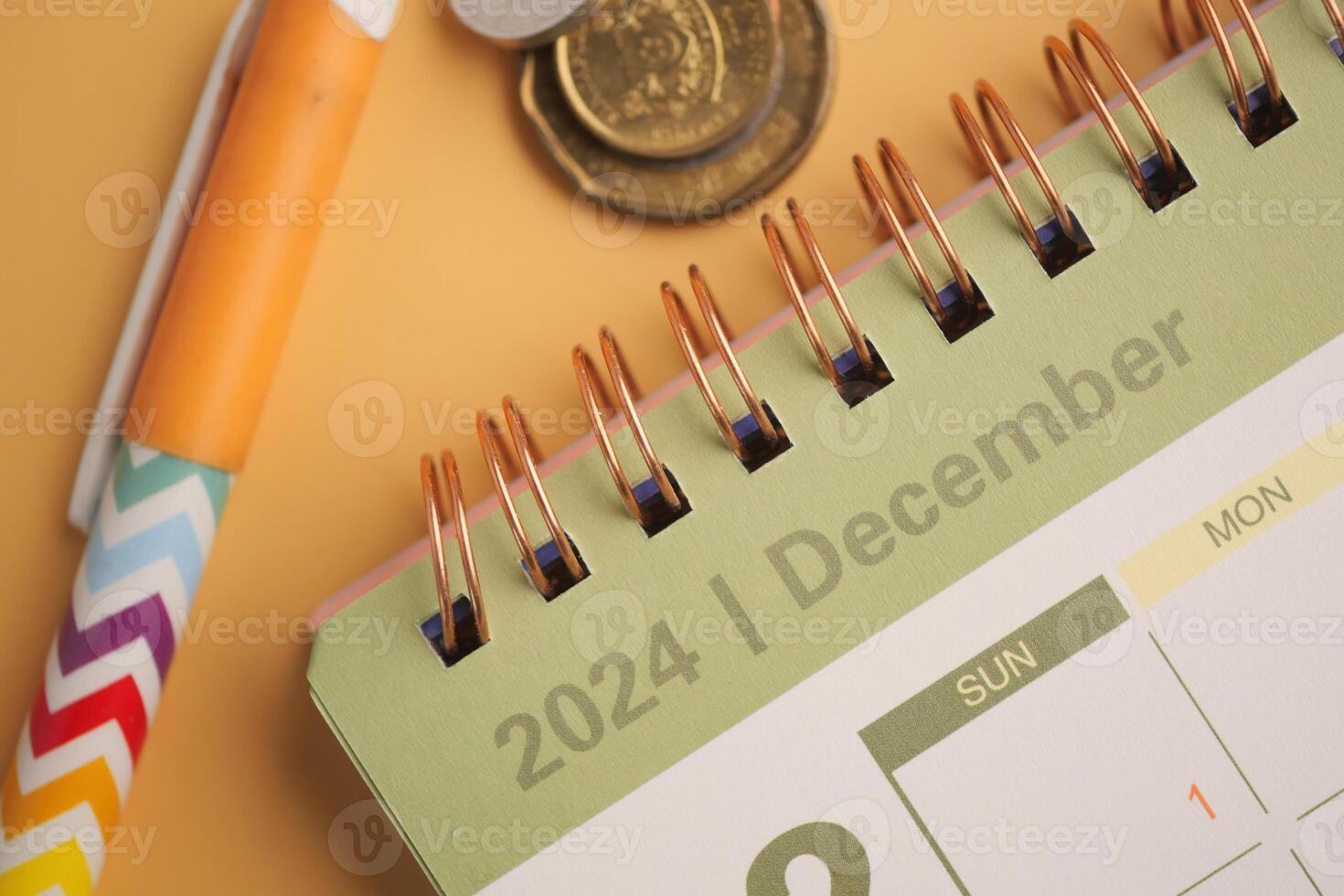The December 2024 Calendar features a Pen and Coins on a vibrant Yellow Background photo