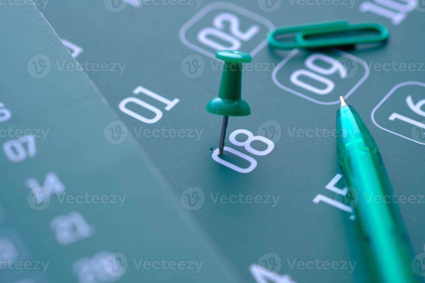 Colorful Calendar Planning Featuring a Green Push Pin and a Pen for Organizing Tasks and Dates photo