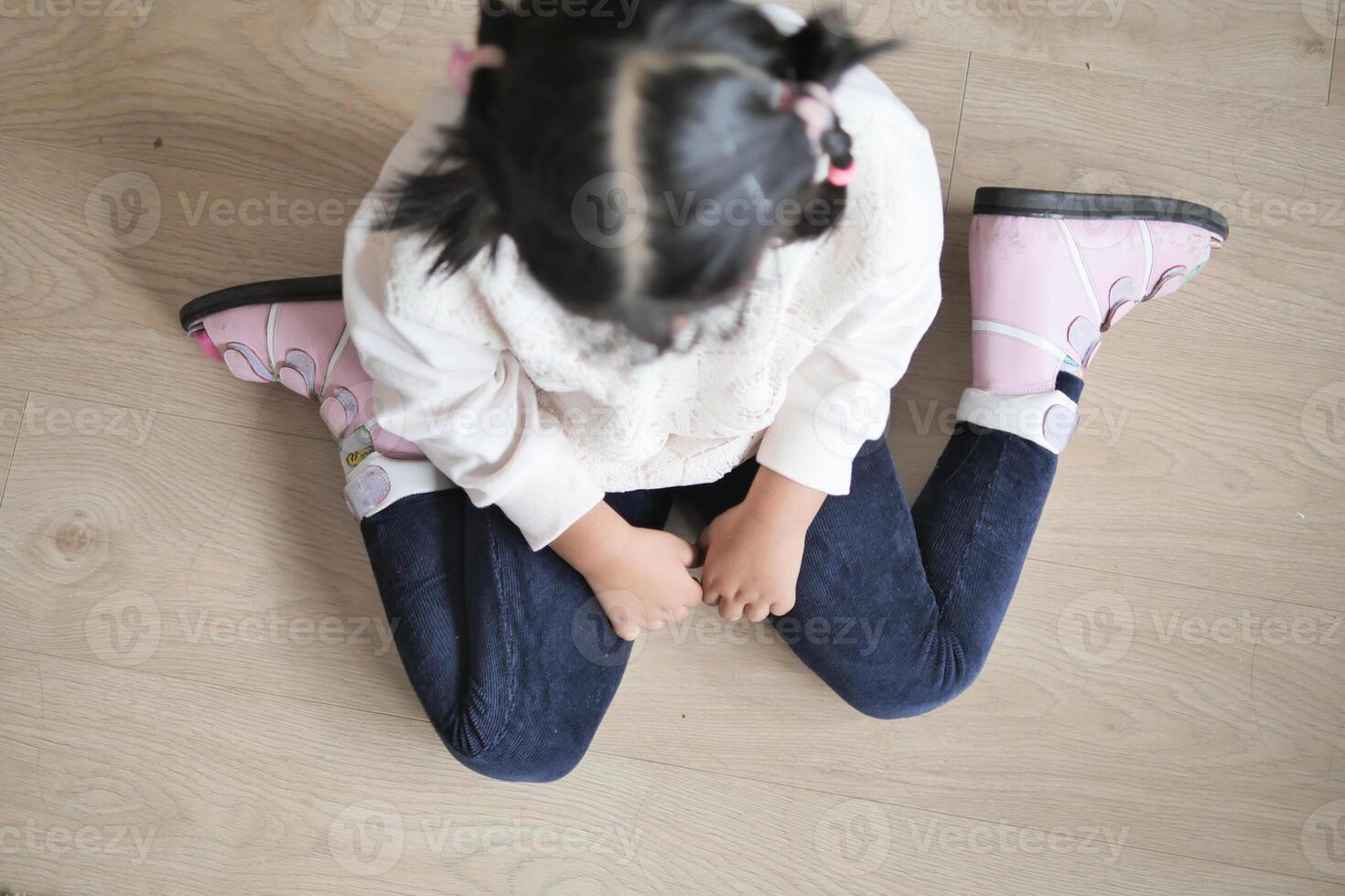 child sitting W posture on the floor . photo