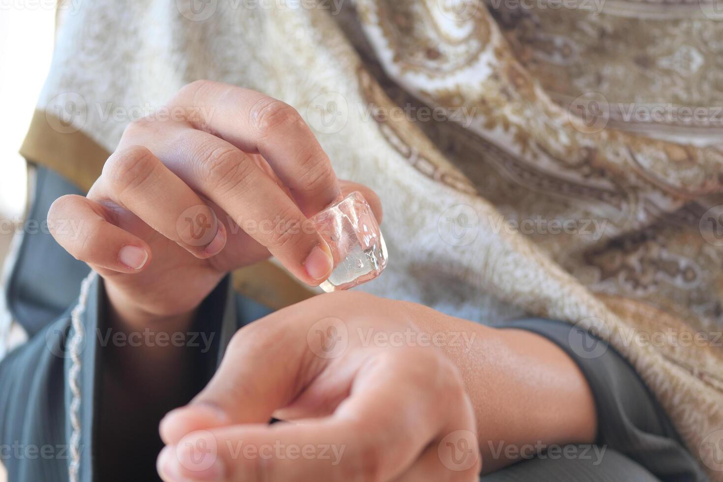 woman rubbing ice cube on his hand. photo