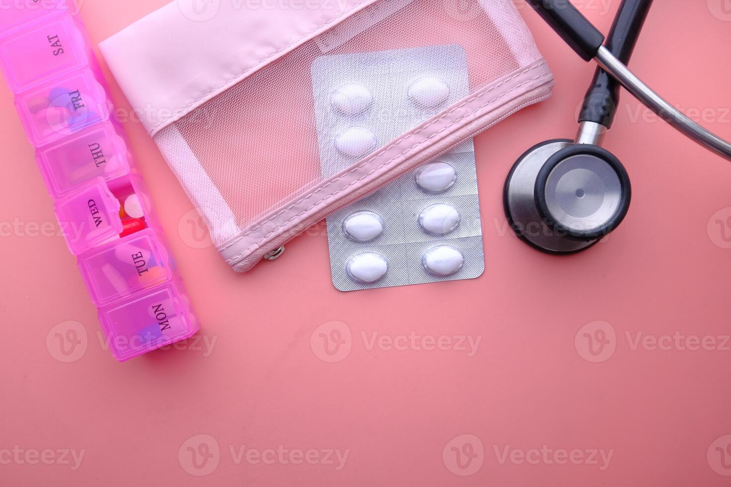 Aesthetic arrangement of medication alongside a stethoscope displayed on a pink background photo