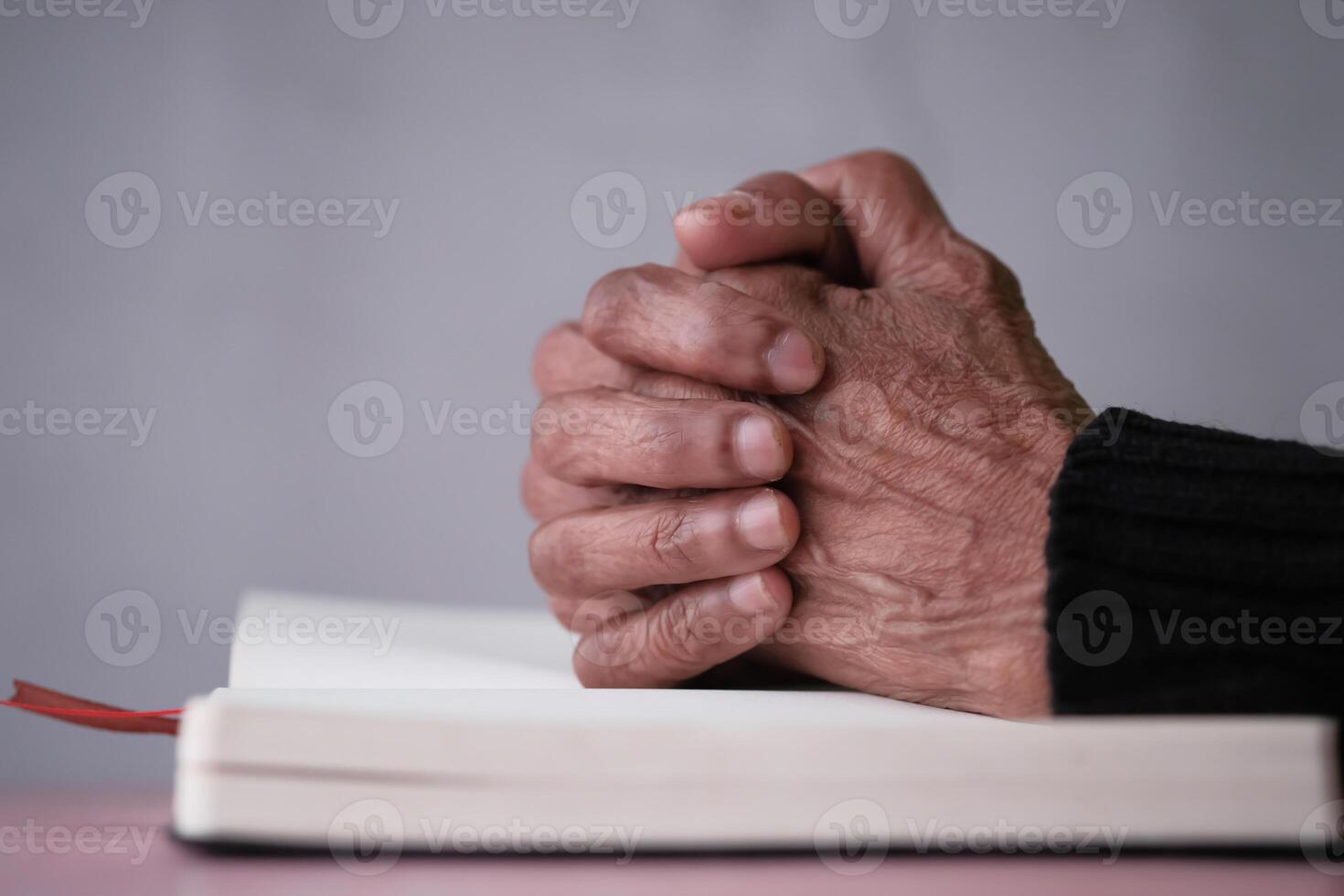 Elderly hands are praying solemnly on an open book that holds significant meaning photo