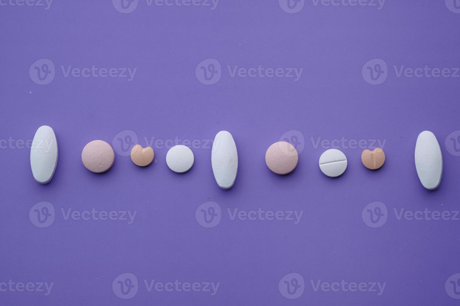 A Collection of Assorted Pills and Tablets Lying on a Deep Purple Background Surface photo