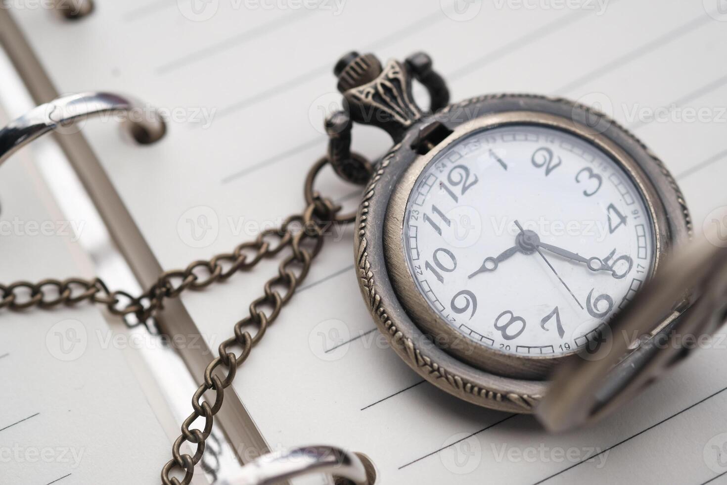 An Exquisite Vintage Pocket Watch Resting Gracefully on an Open Planner or Diary Page photo