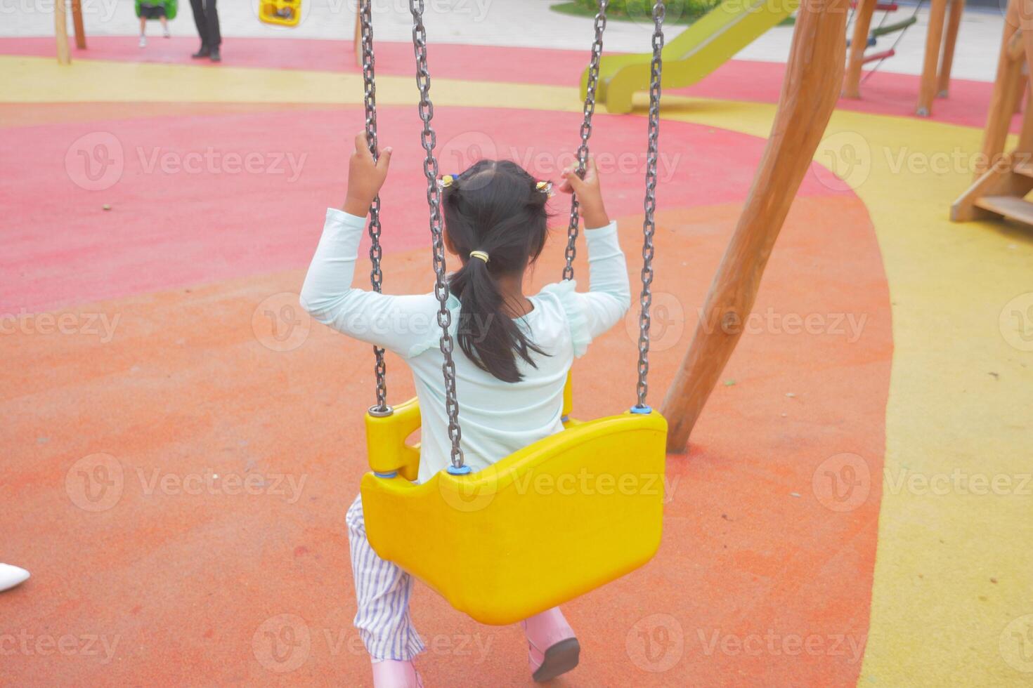 A Cheerful Child Having Fun While Swinging on a Vibrant and Colorful Playground Slide photo