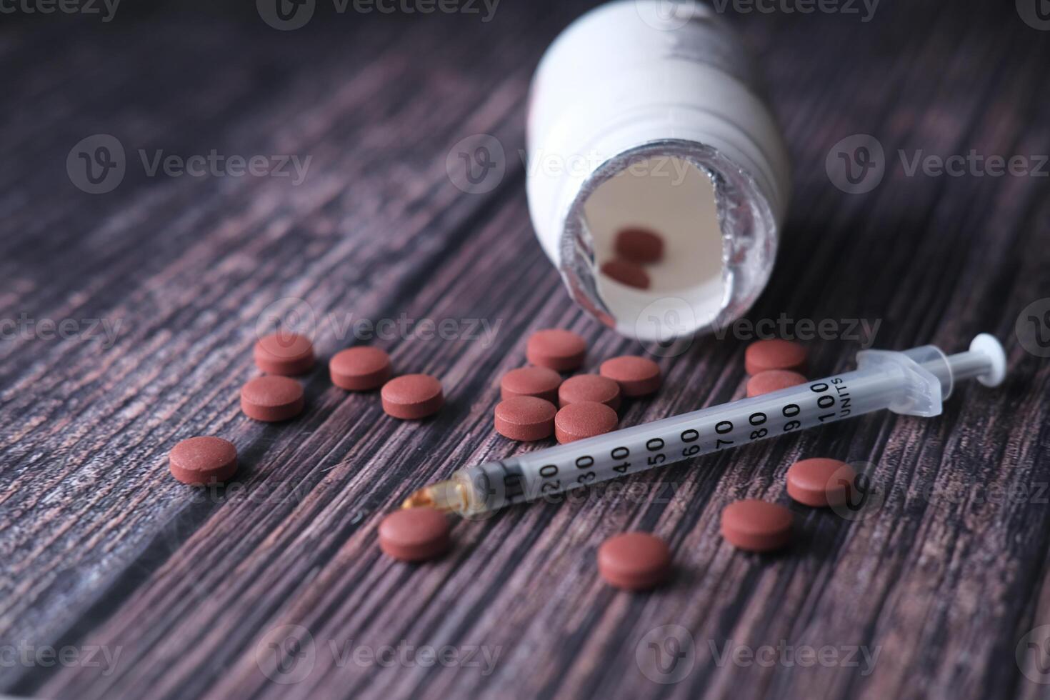 Medical Supplies A combination of Pills and a Syringe arranged on a Wooden Background surface photo