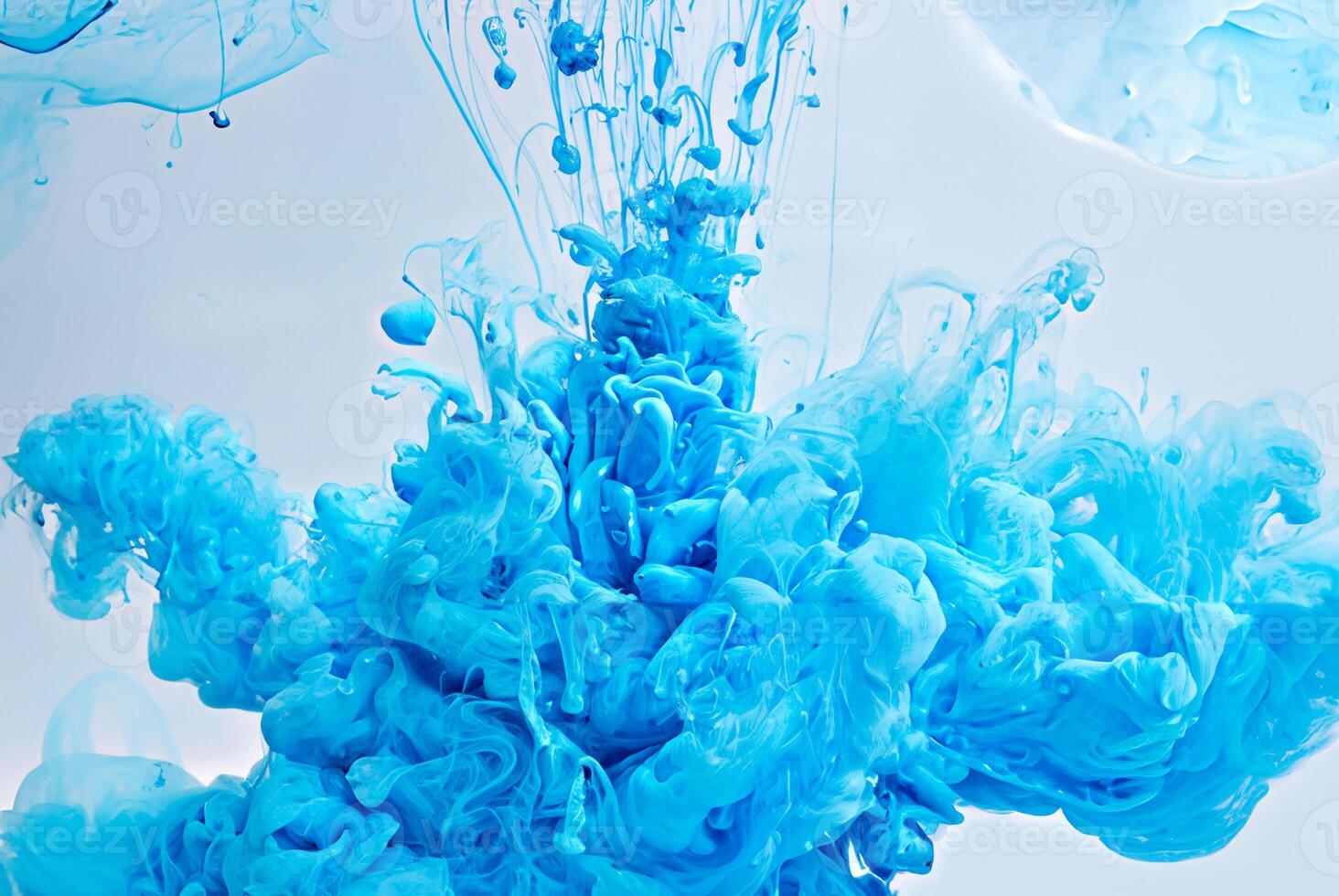 Abstract closeup of vibrant blue ink swirling and dispersing in water, creating cloud-like shapes in a fluid dynamic motion. photo
