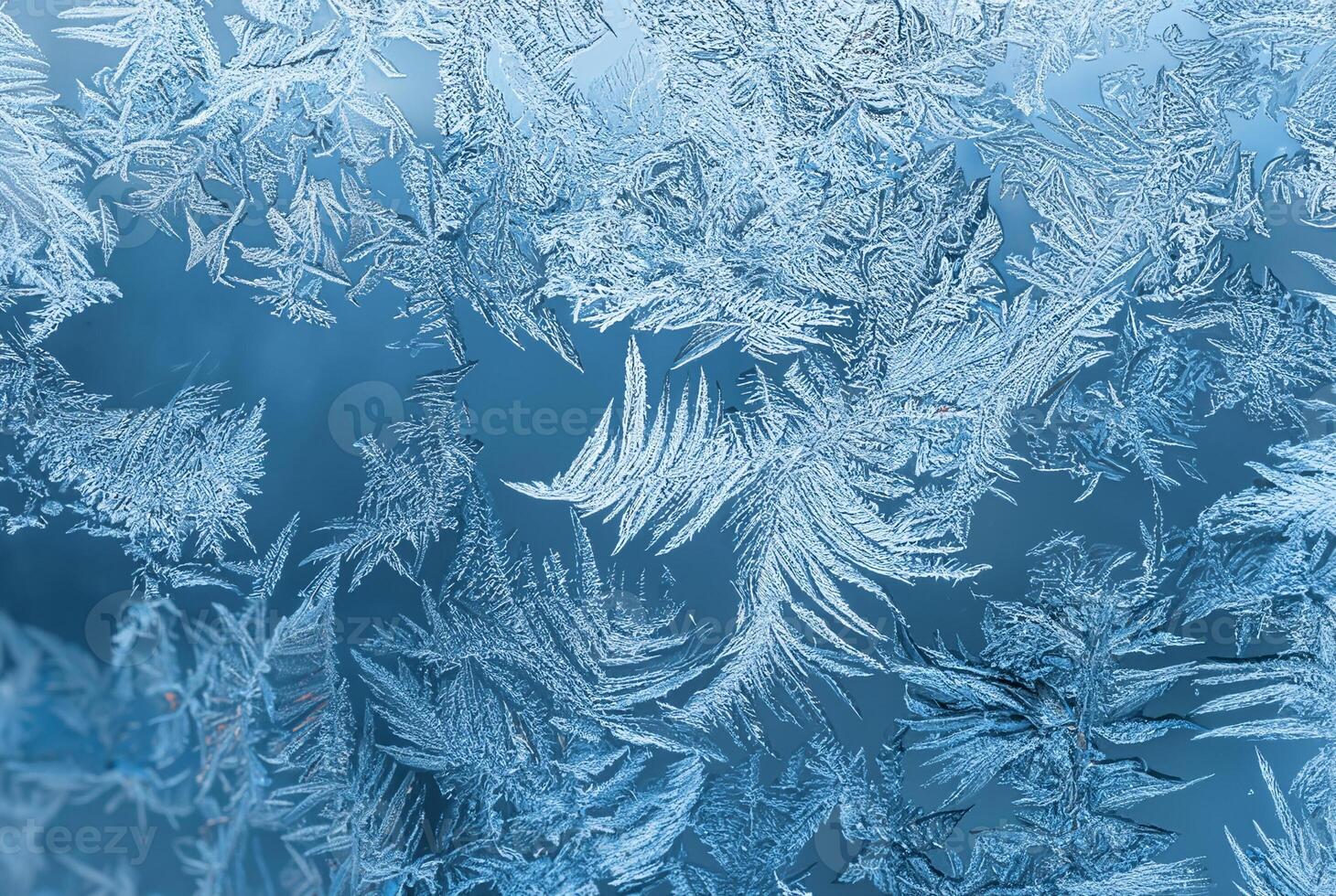 Detailed macro view of intricate frost patterns on a window surface during winter, forming natural ice crystals. photo