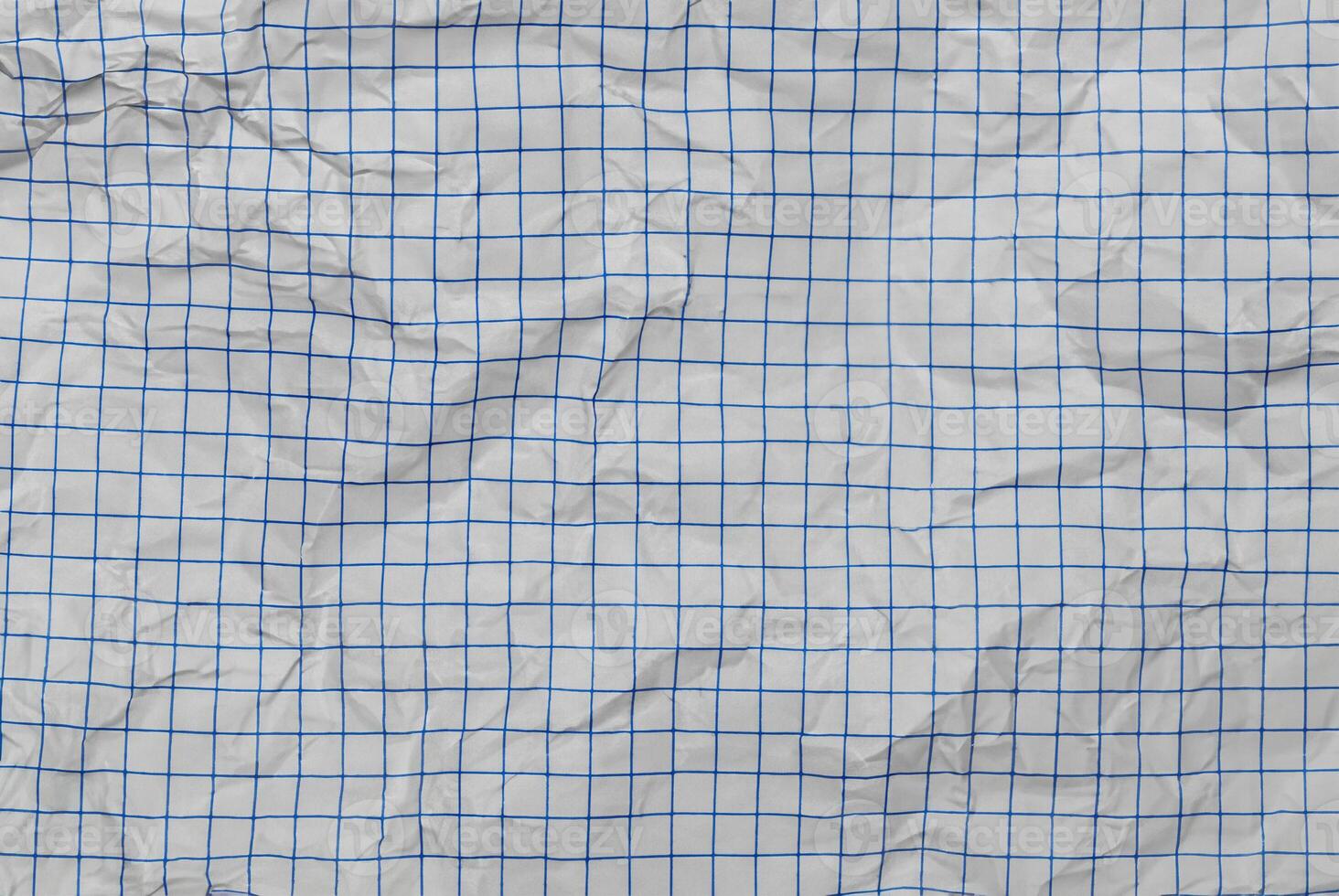 Close-up of crumpled white paper with a blue grid pattern, perfect for abstract backgrounds or textures. photo