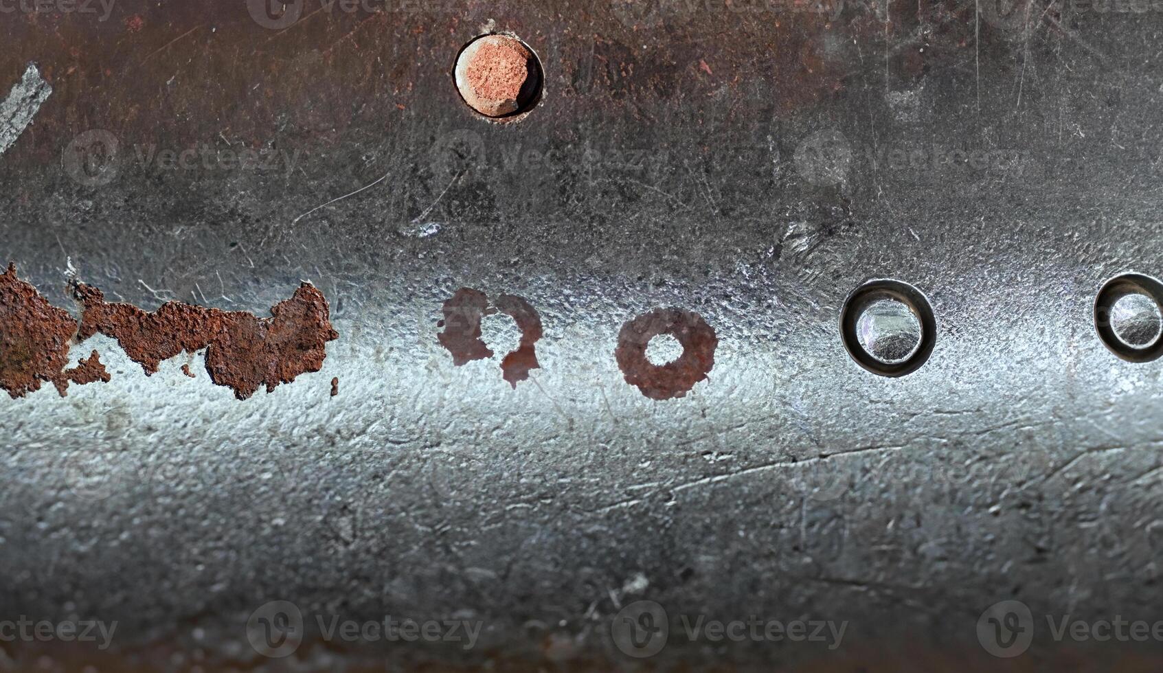 Close-up of a rough metallic surface featuring scratches, dents, and weathered texture, ideal for industrial backgrounds. photo