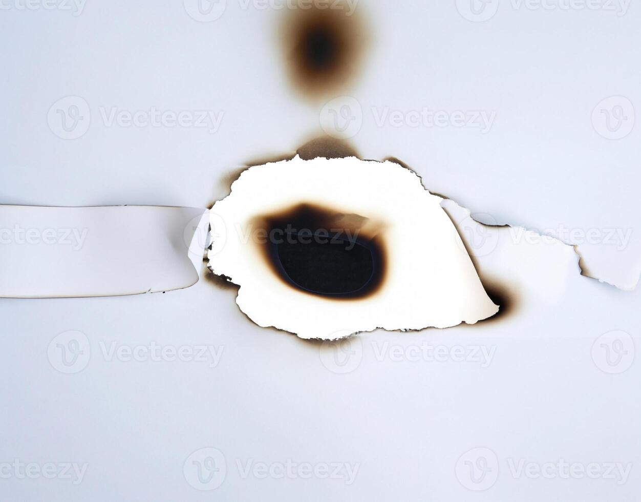 A burnt hole in white paper with singed edges, offering a unique texture for design elements or backgrounds. photo