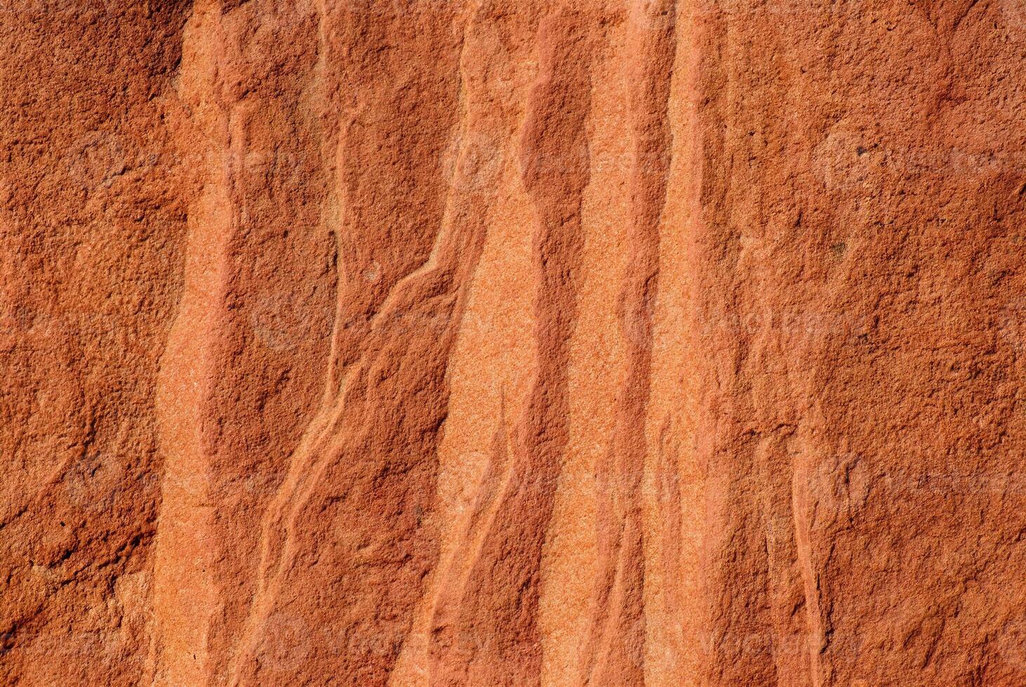 Close-up of red sandstone rock texture featuring natural wavy patterns and rough surface. photo