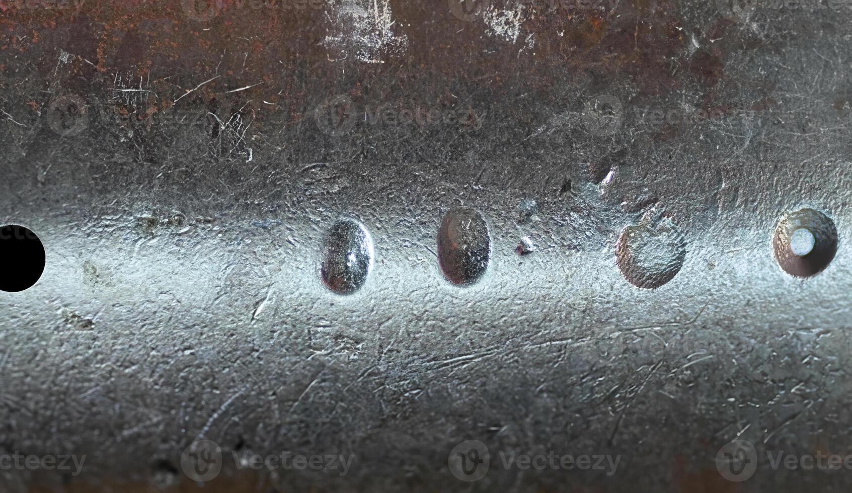 Close-up of a rough metallic surface featuring scratches, dents, and weathered texture, ideal for industrial backgrounds. photo