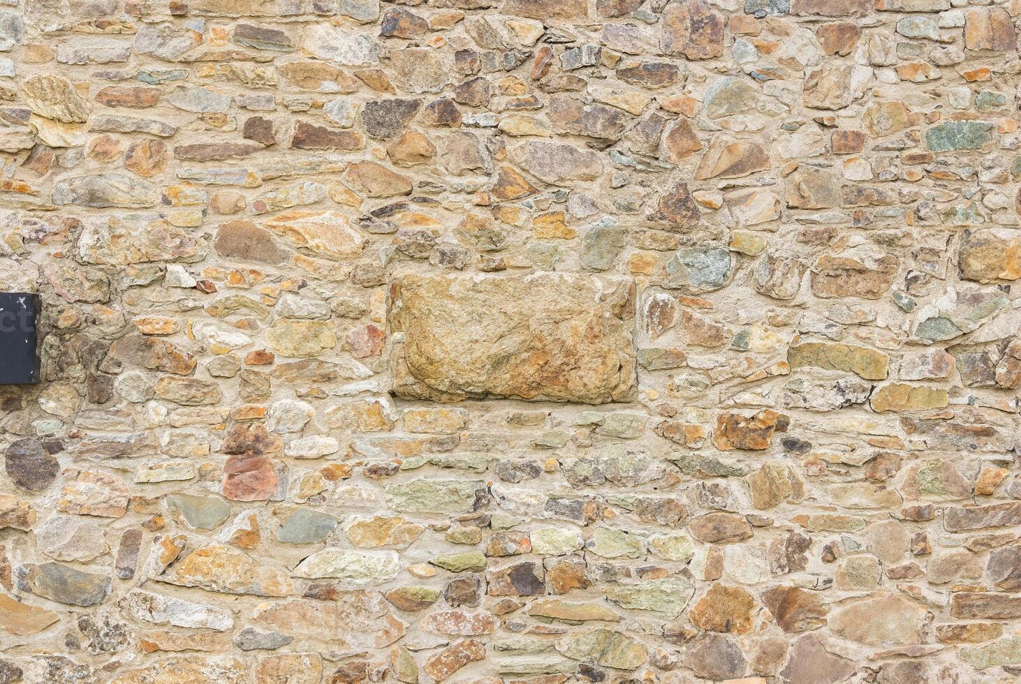 Close-up of a natural stone wall with rough texture and uneven stones, perfect for backgrounds. photo