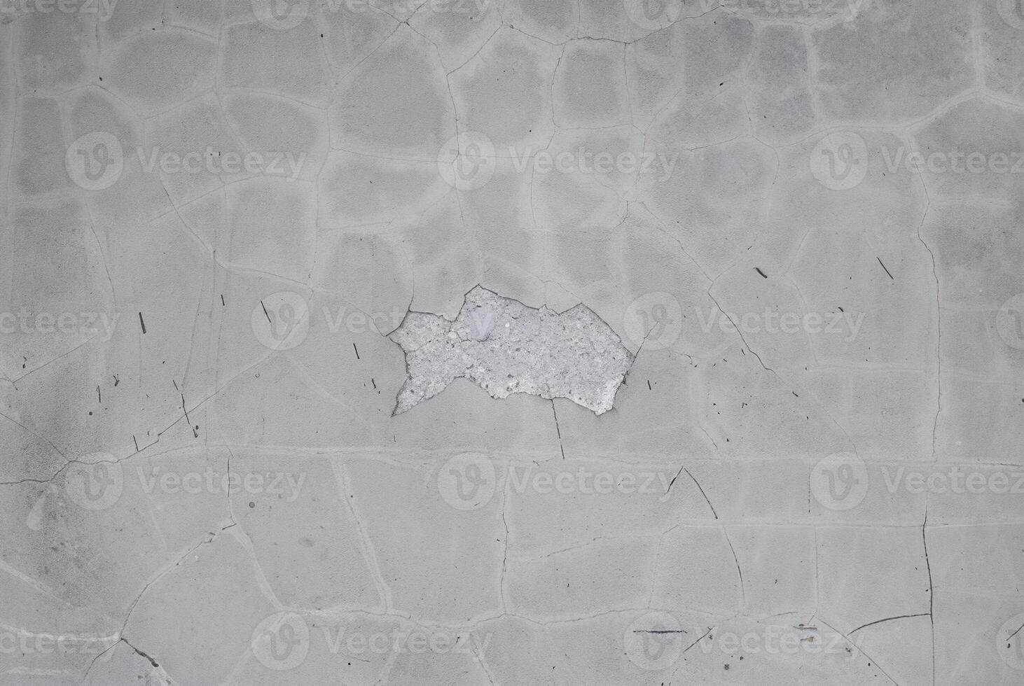 Textured concrete surface with visible cracks and faint scratches, offering a neutral and industrial background. photo