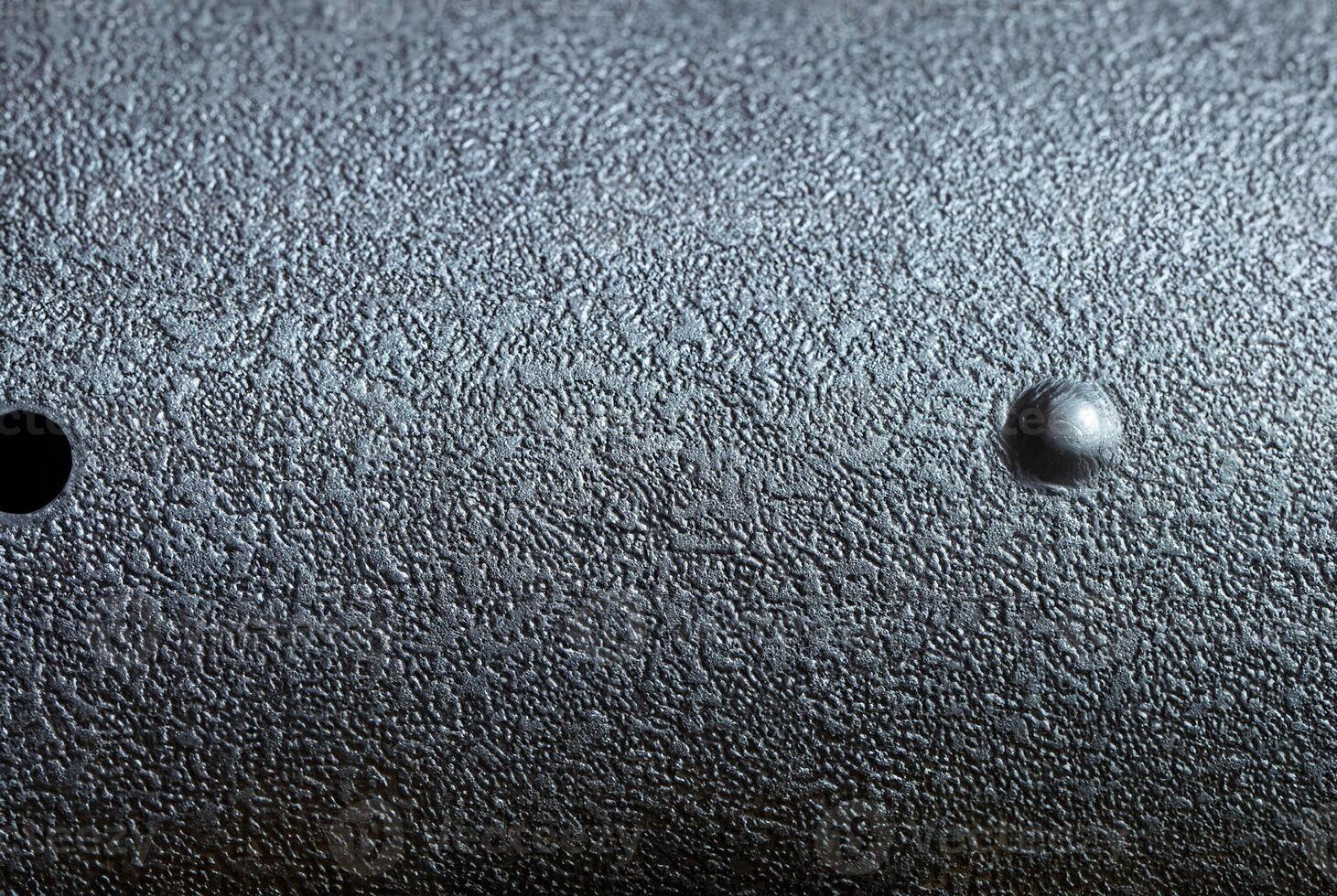 Close-up of dark metallic surface with rough texture, ideal for industrial design, backgrounds, and material projects. photo