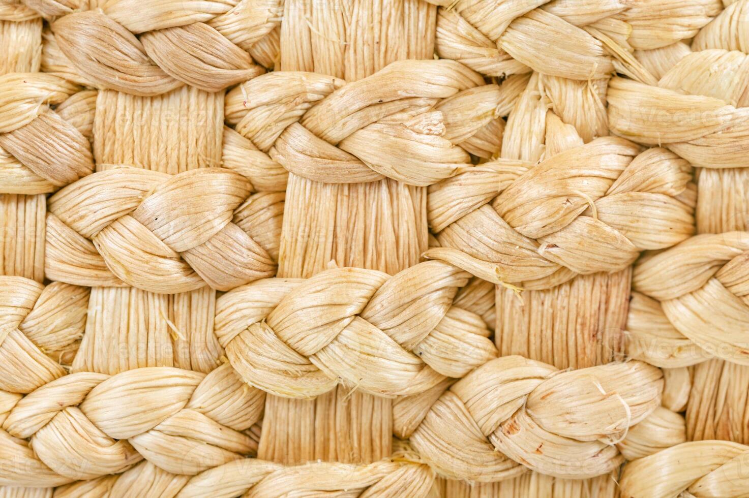 Macro shot of woven natural fibers, showcasing a detailed and textured pattern of braided straw or wicker material. photo