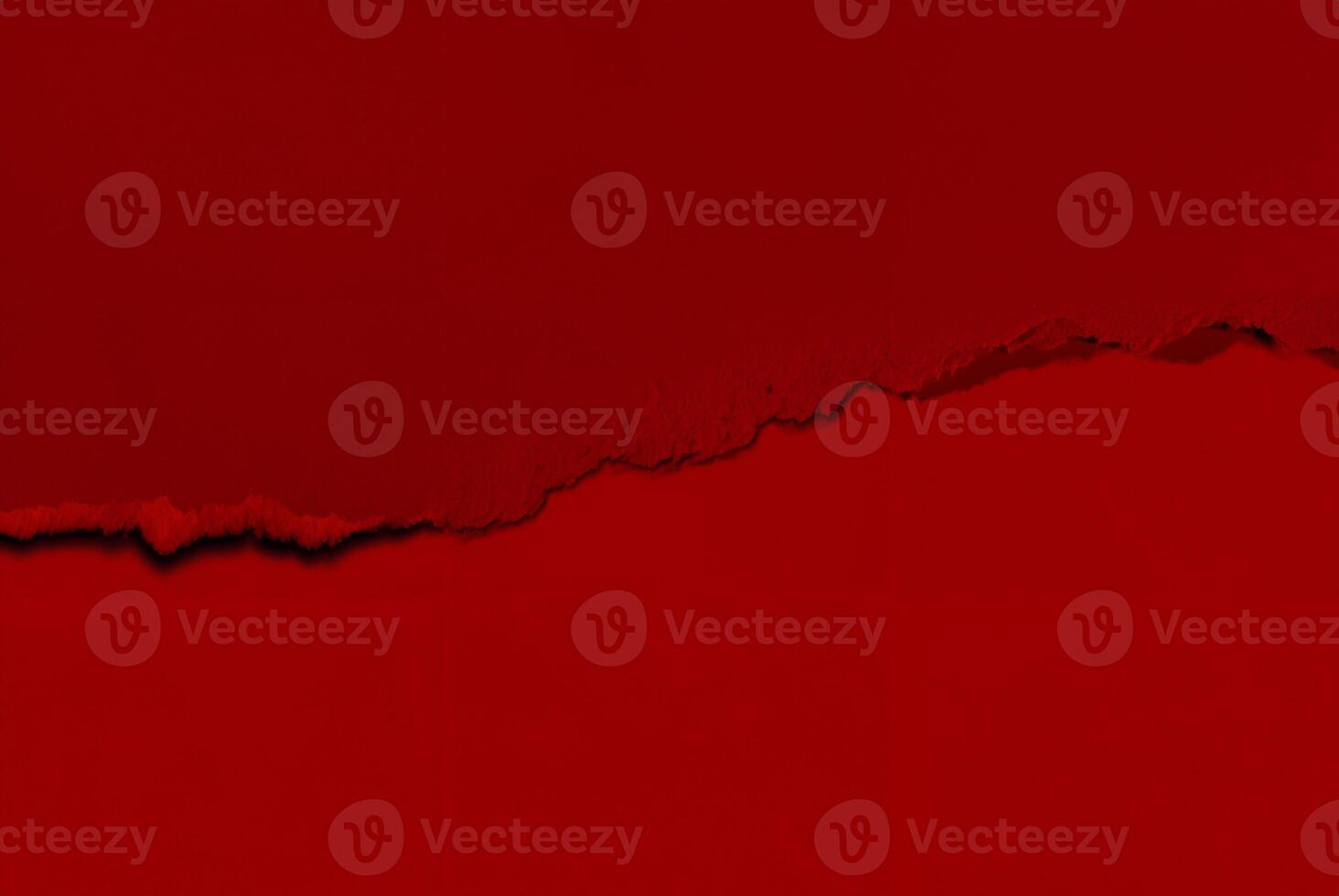 Close-up of a torn red paper texture with a rough edge, perfect for use as an abstract background or design element. photo
