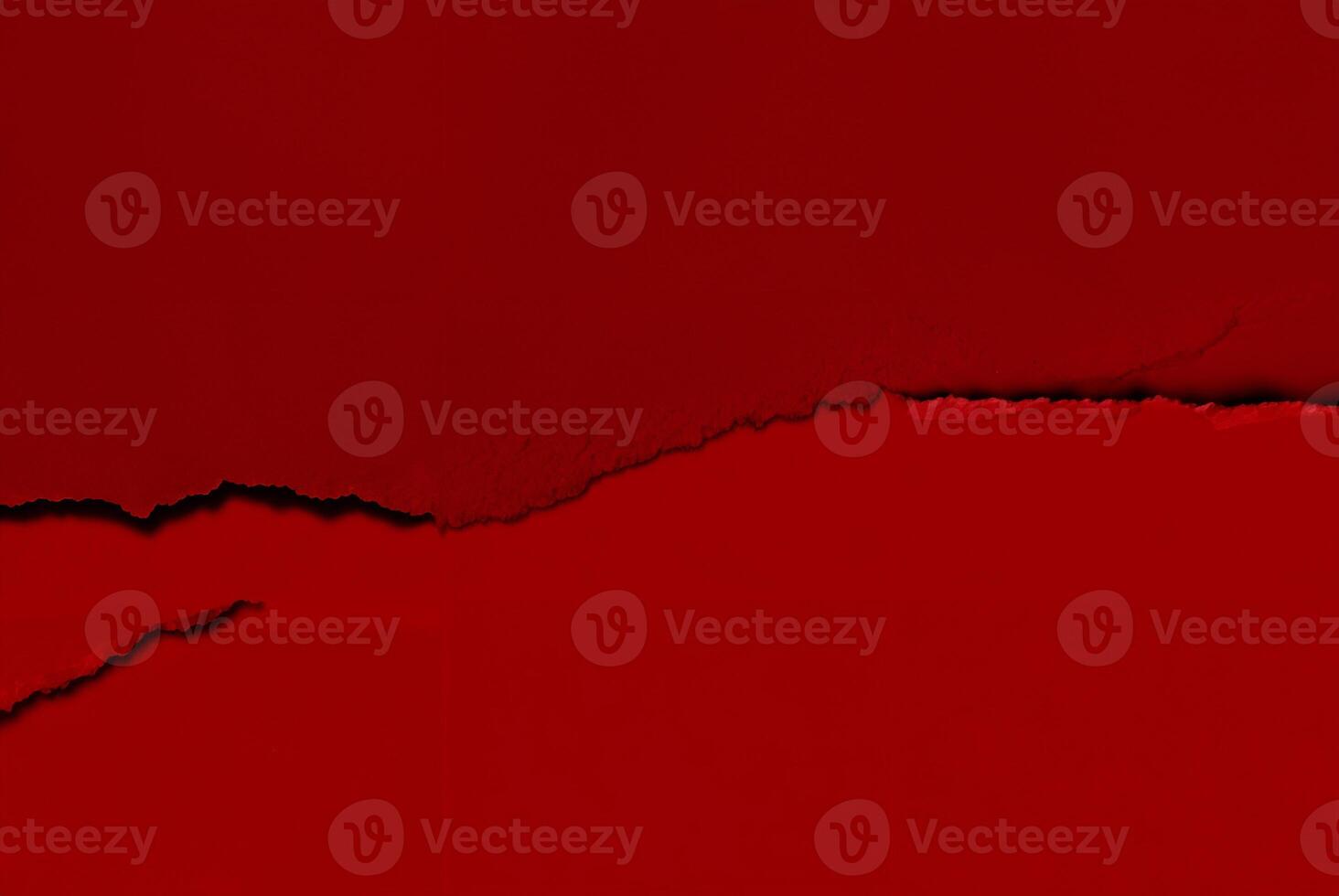 Close-up of a torn red paper texture with a rough edge, perfect for use as an abstract background or design element. photo