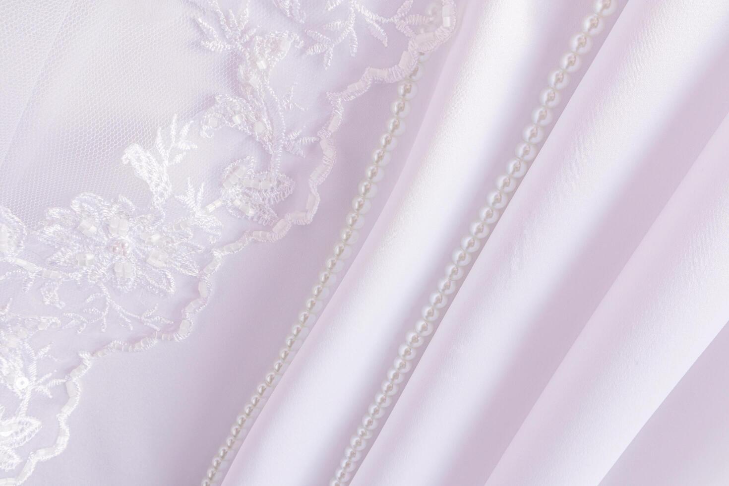 Chic wedding backdrop for design with waves of white satin fabric, pearl beads and part of a lace veil. A copy of the space. photo