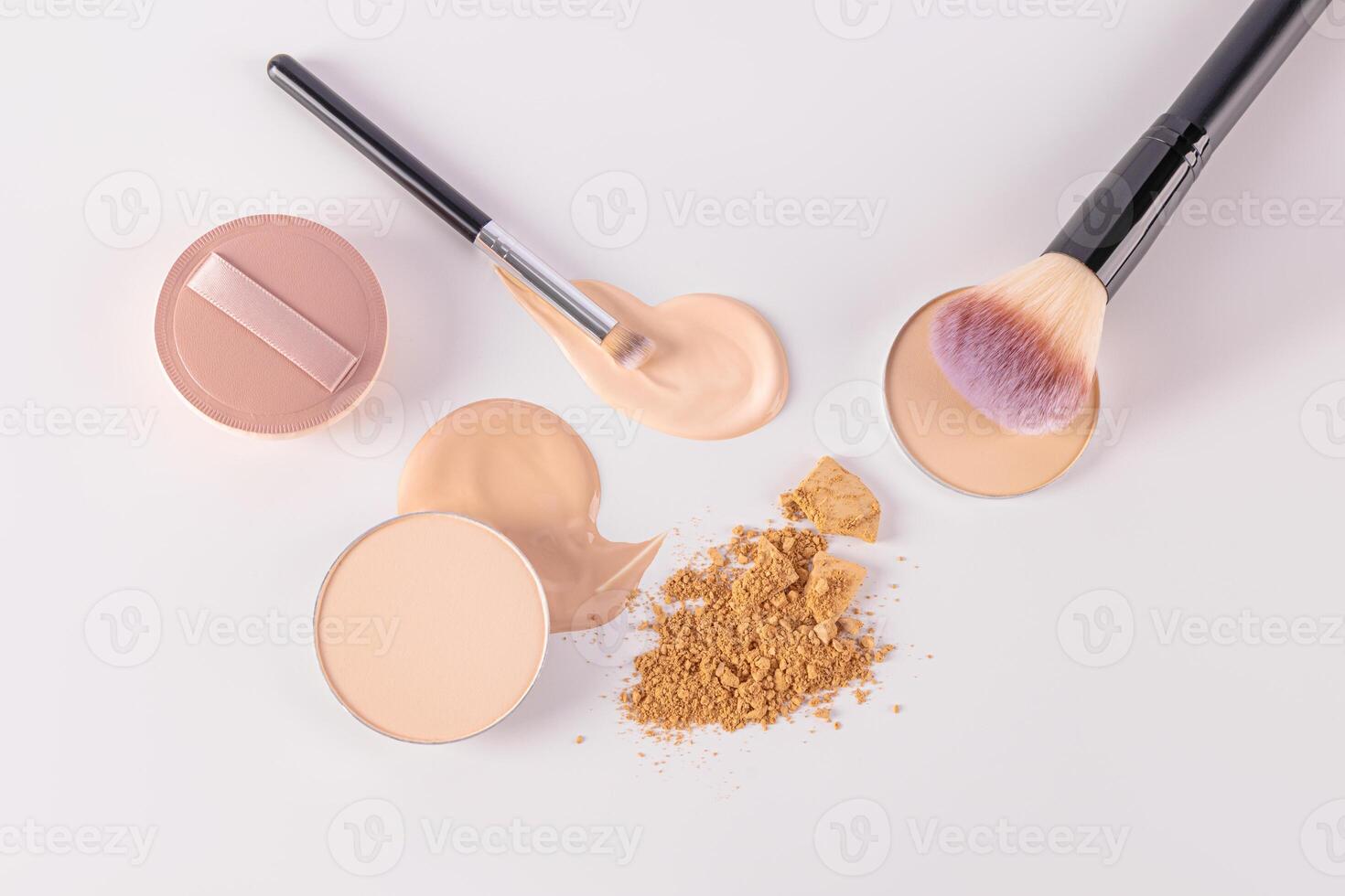 Delicate cosmetic background in light colors with two makeup brushes, a round sponge on a sample of foundation liquid powder. top view. Flat lay. photo