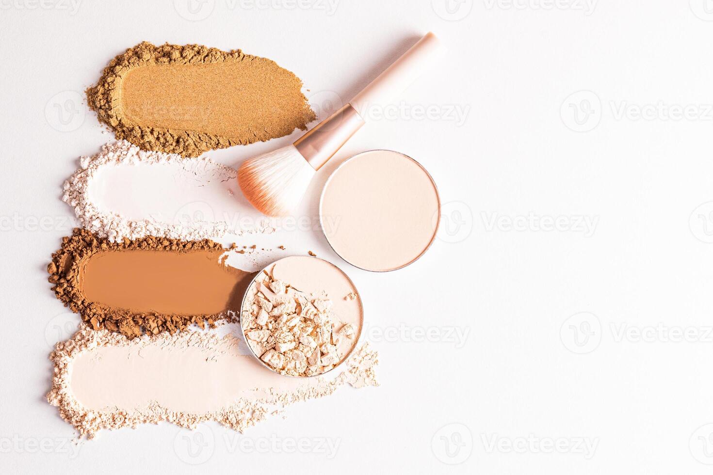 Beautiful loose powder samples in different tones, two blocks of compact powder and a makeup brush on a light background. top view. A copy space. photo