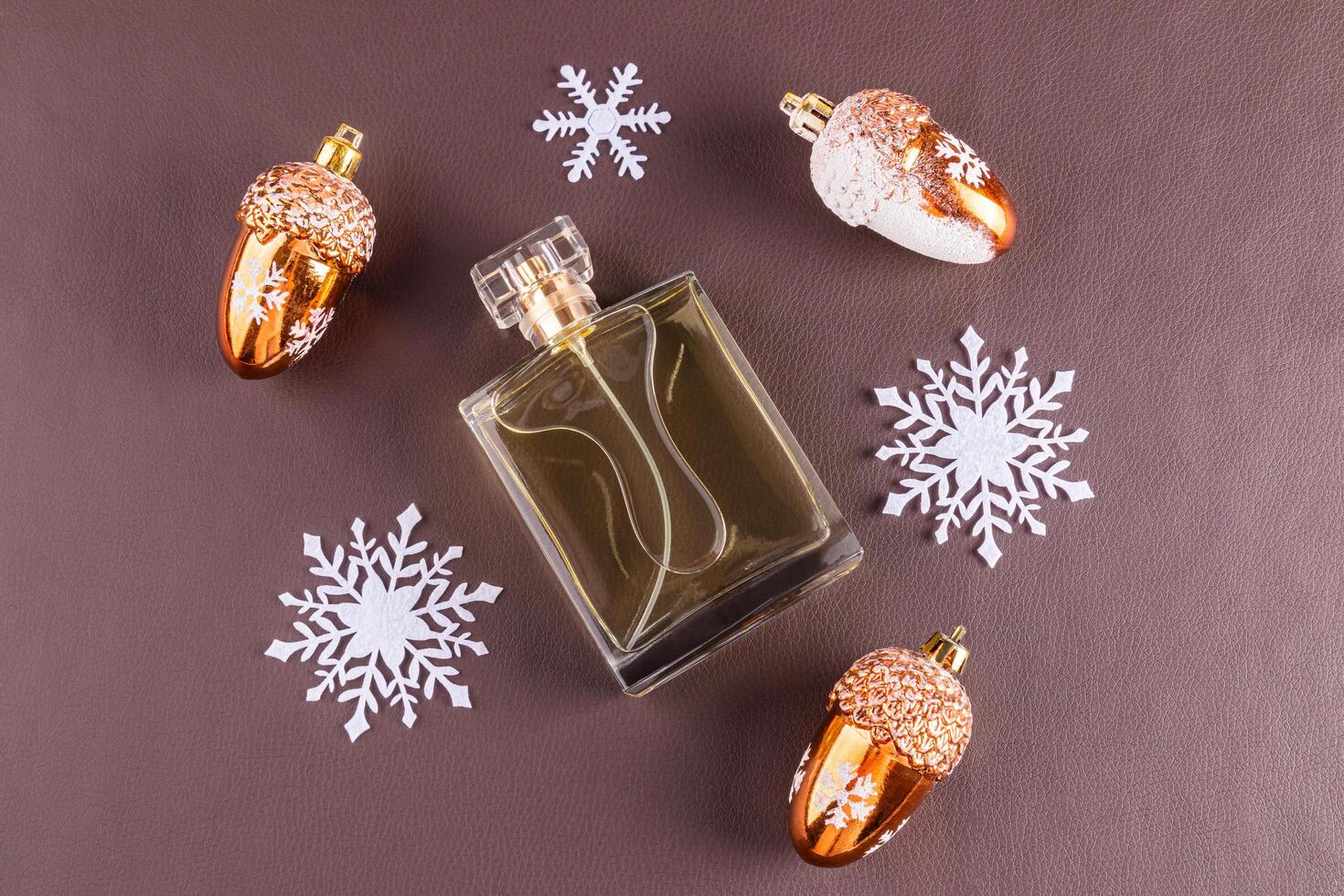 A chic bottle of expensive perfume on a leather brown background with white snowflakes. Blank mockup perfume bottle. template. top view. photo