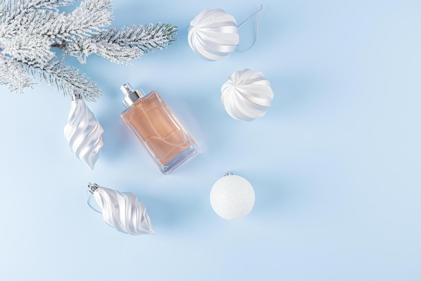An unbranded perfume bottle on a blue background among decorative snowflakes and golden stars. top view. A copy space. blank bottle mockup. template photo