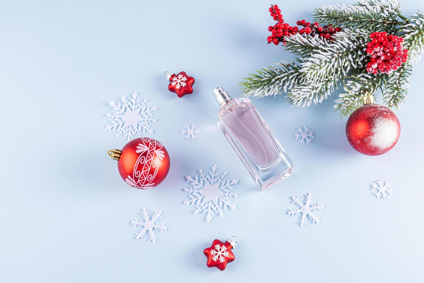 An unbranded perfume bottle on a blue background among decorative snowflakes and golden stars. top view. A copy space. blank bottle mockup. template photo