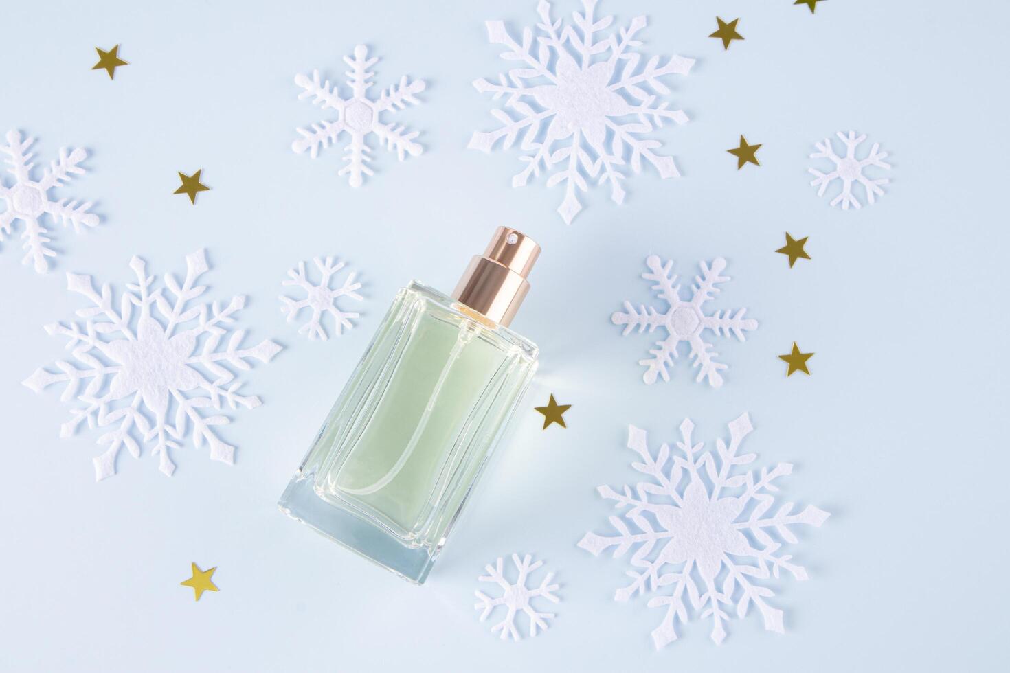 An elegant bottle of cosmetic spray or perfume on a blue festive background with snowflakes and gold stars. Blank bottle mockup. template. top view. photo