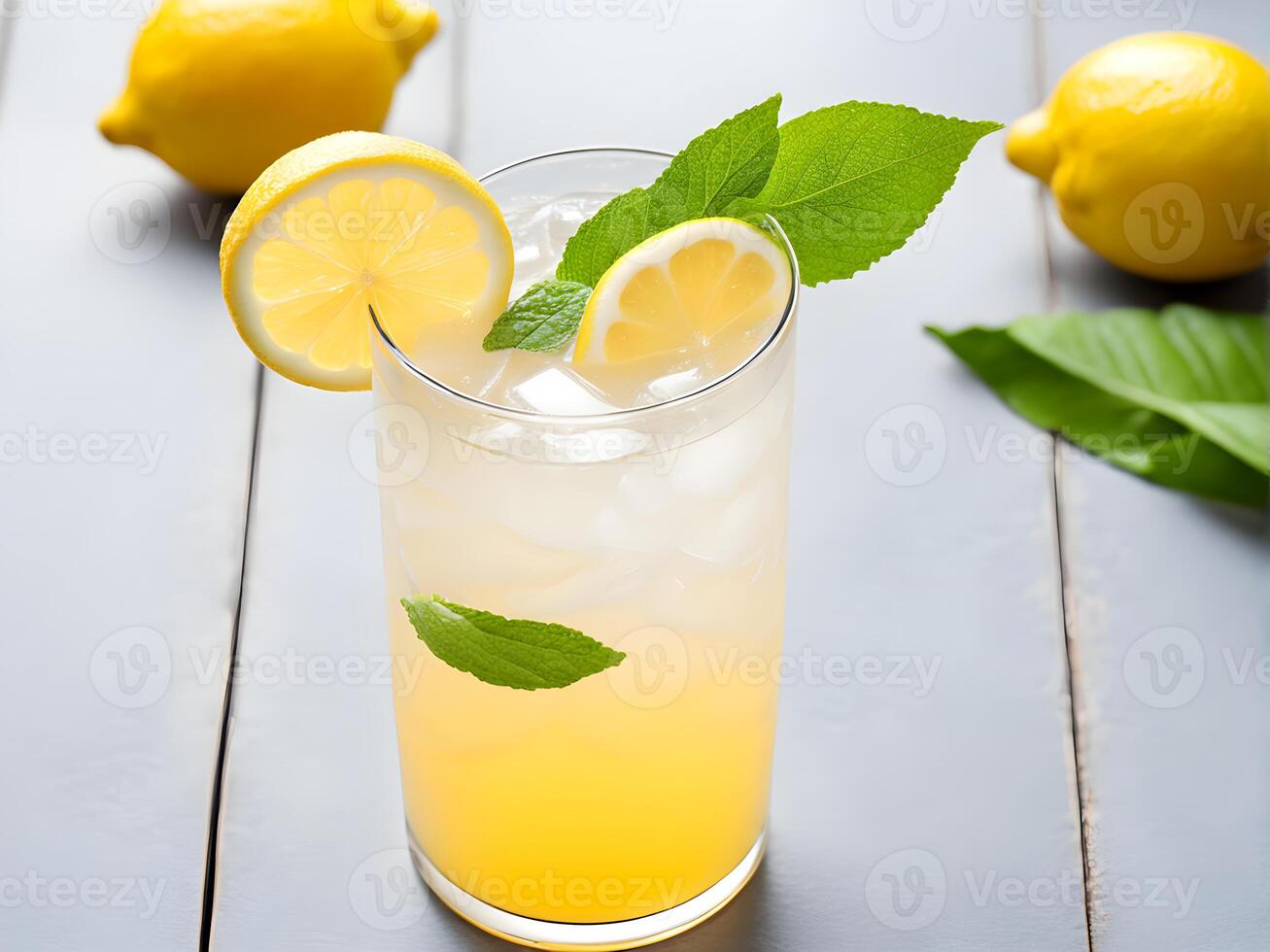 Close up high angle view of lemonade juice in glass on white wooden table adorned with lemon sliced and mint leaf decorated by two lemon fruit photo