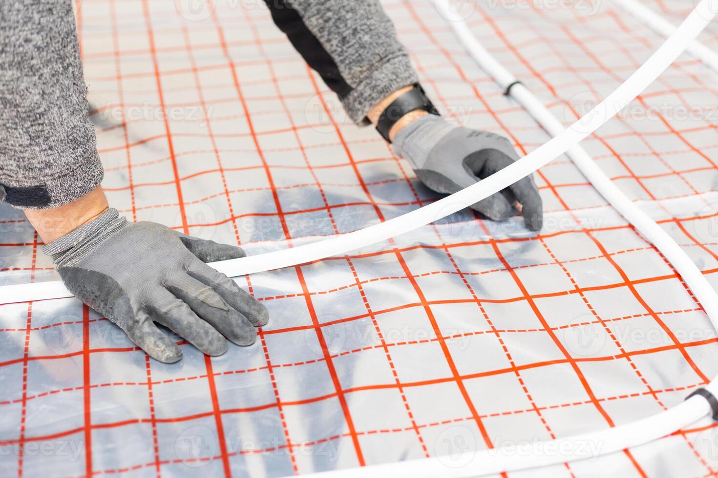 Worker installing underfloor heating system, water heating on the new residential house, concept of heated floor photo