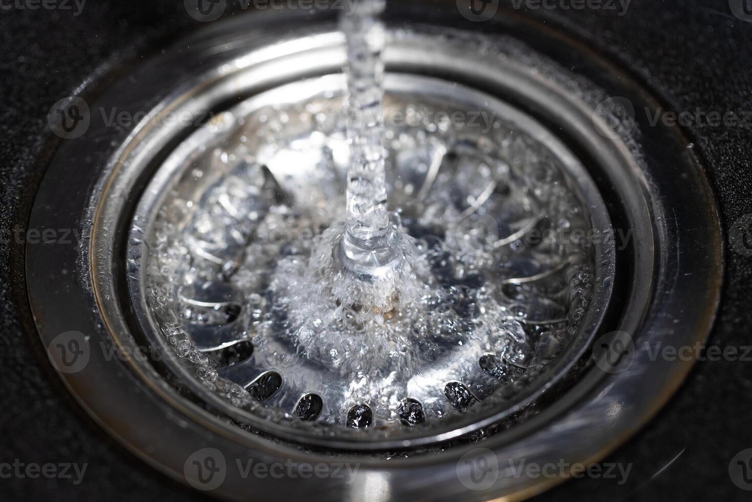 The water falling down from faucet to stainless sink and flow down to water hole, drink concept photo