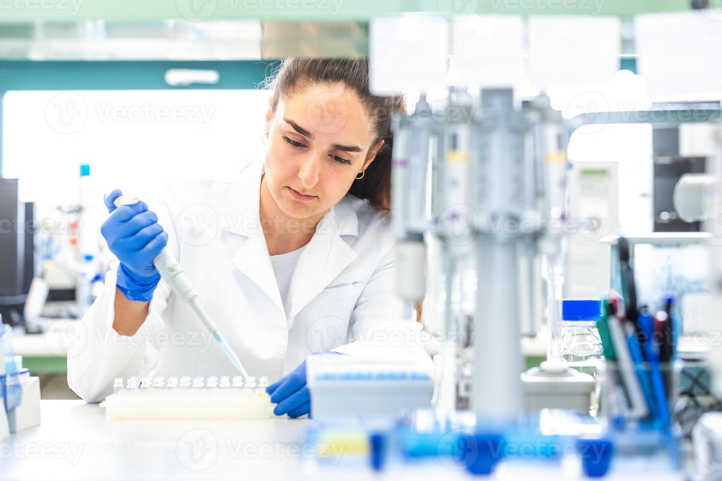Scientist with dropper dripping liquid into a test tube in scientific laboratory, concept of pharmaceutical environment photo