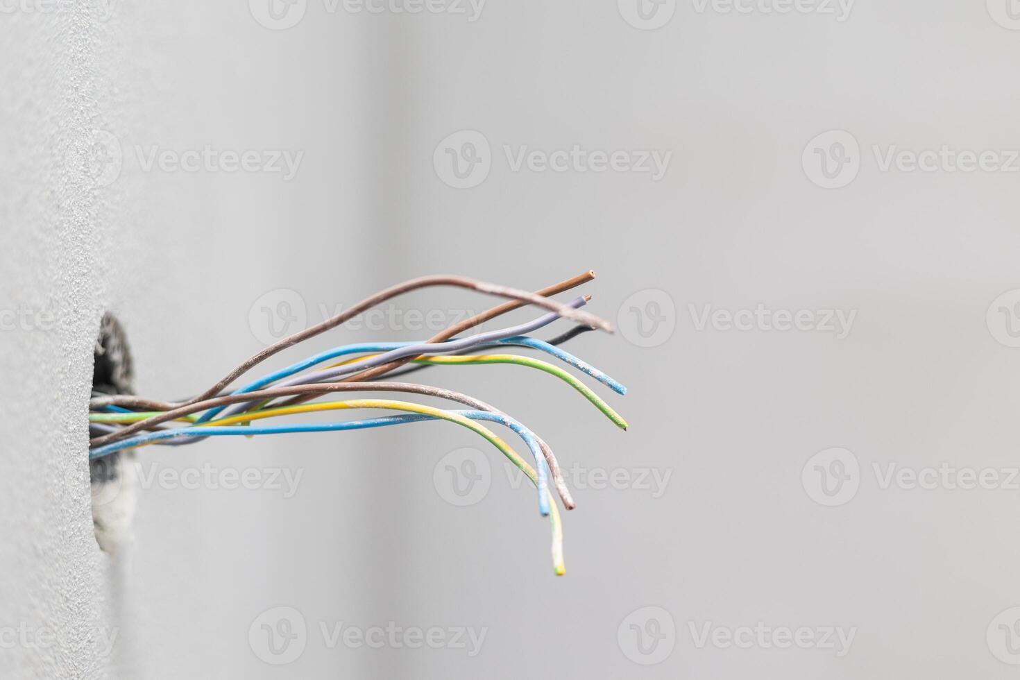 Open electric plug at home with kind of seen cables, electrical wires, wiring, socket on an old concrete building wall photo
