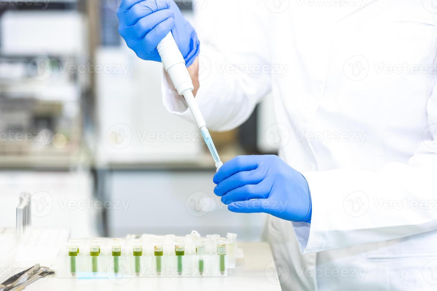 Scientist with dropper dripping liquid into a test tube in scientific laboratory, concept of pharmaceutical environment photo