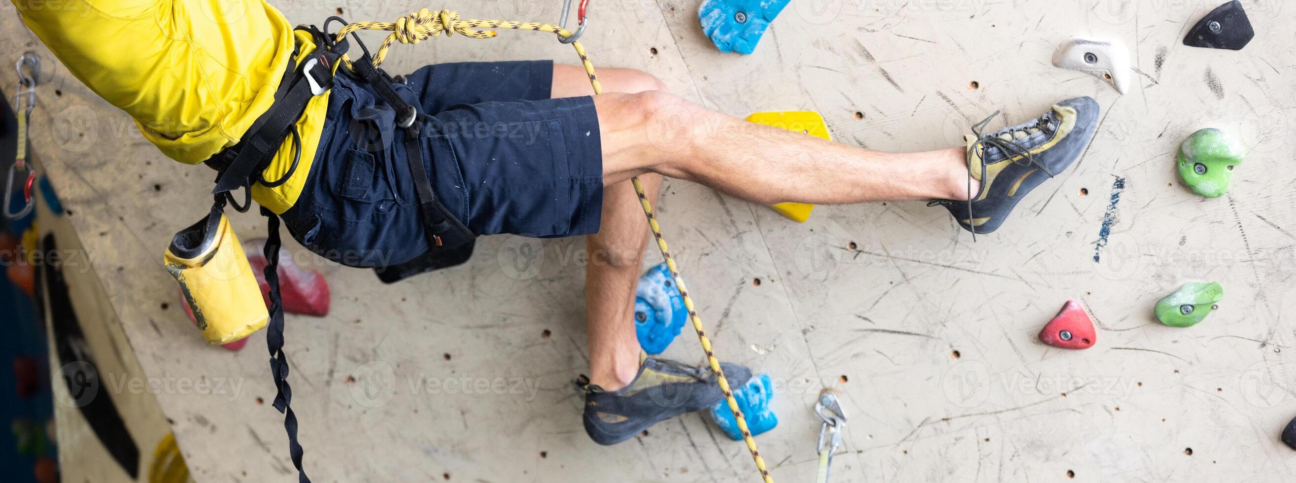 Close up view of young man or climber feet in climbing shoes on artificial indoor wall at the climbing center, sport activity concept photo
